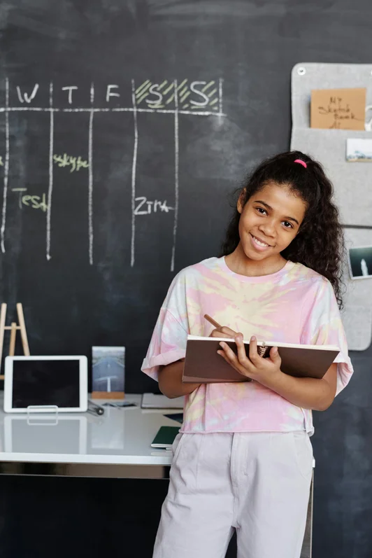 jeune fille souriante et confiante devant un tableau de classe