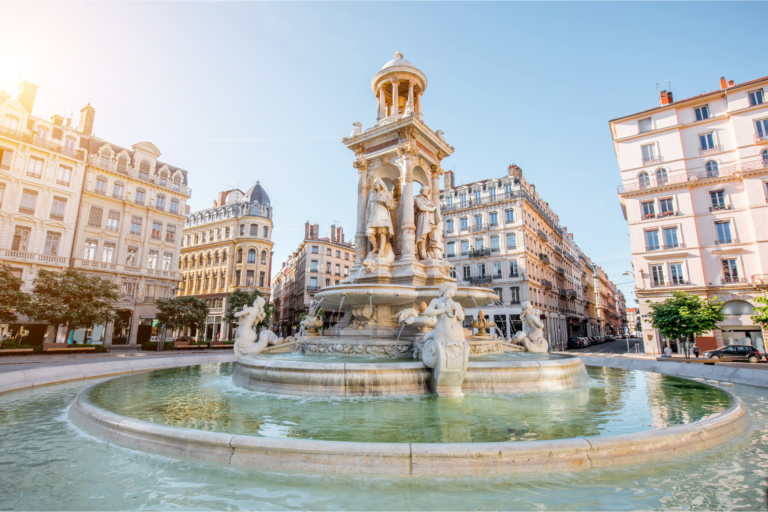 Place des Jacobins à Lyon 2 avec sa fontaine centrale, architecture haussmannienne et bassin en eau sous un ciel lumineux.